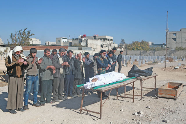 Syrians pray in front of the body of a victim during his funeral following a reported air strike in the rebel-held besieged town of Arbin, in the Eastern Ghouta region on the outskirts of Damascus, on Saturday (AFP photo)