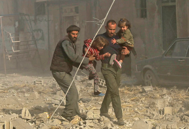 Syrians run with their children following reported government air strikes over residential areas in the rebel-held eastern Ghouta region in Damascus, Syria, on  Sunday (Anadolu Agency photo)