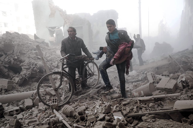 A young Syrian man carries a wounded child following reported government air strike on the rebel-held town of Douma, on the eastern outskirts of the capital Damascus, on February 25 (AFP photo)