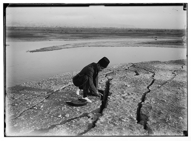   Palestinian man using his rifle to test the depth of a crack caused by the 1927 earthquake (Photo courtesy of CBRL Amman Institute)
