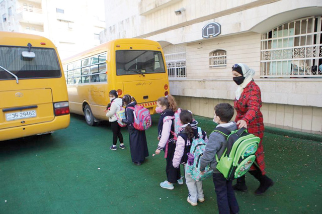 Students are seen waiting to board a school bus in Amman on Sunday (Photo by Osama Aqarbeh)