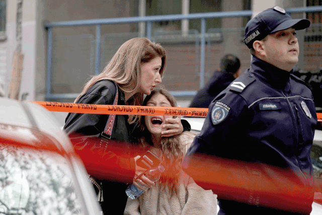 A parent escorts her child following a shooting at a school in the capital Belgrade on Wednesday (AFP photo)