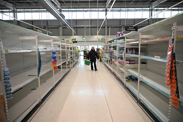 A shopper walks past empty toilet roll shelves in Manchester, northern England on March 20, Friday (AFP photo)