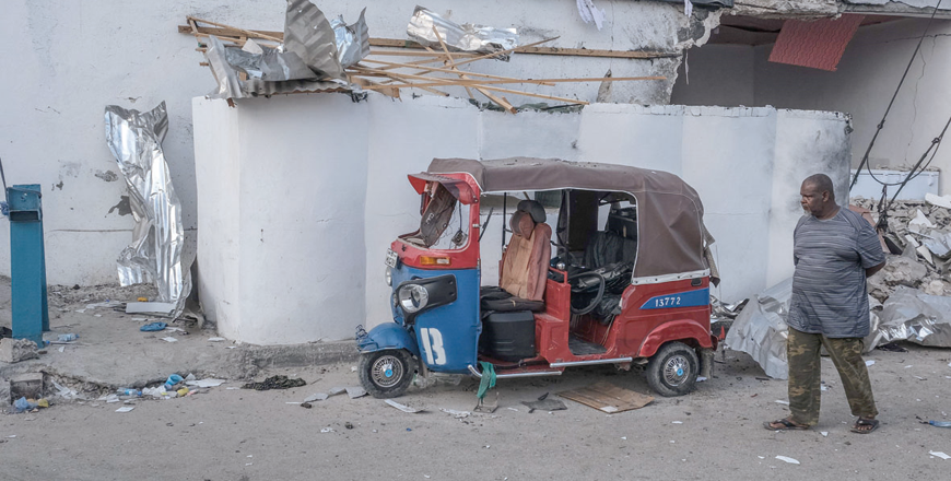 A man walks past a damaged tuk-tuk left outside the site of an attack at the Pearl Beach Hotel in Mogadishu on Saturday (AFP photo)