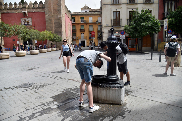 People cool off to fight the scorching heat during a heatwave in Seville, Spain, on Monday (AFP photo)