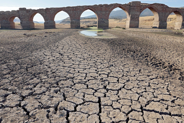 Part of the Guadiana river has dried up and gives way to dry land under the Puente de la Mesta mediaeval bridge in Villarta de los Montes, in the central-western Spanish region of Extremadura, on Tuesday (AFP photo)