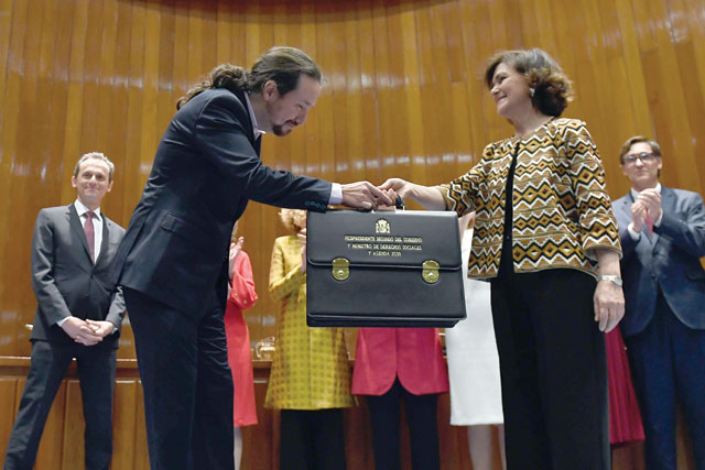 Spain's newly appointed Deputy Prime Minister for Social Rights and Sustainable Development Pablo Iglesias (left) receives his briefcase from Spain's Deputy Prime Minister Carmen Calvo during a ceremony in Madrid on Monday (AFP photo)
