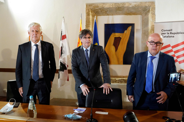 In this file photo taken on October 4, 2021, Catalonia's exiled former leader Carles Puigdemont (centre) flanked by his Italian lawyer Agostinangelo Marras (left) and his Spanish lawyer Gonzalo Boye, prepares to address the media during a press conference in Alghero, Sardinia, Italy, after his extradition hearing (AFP photo)