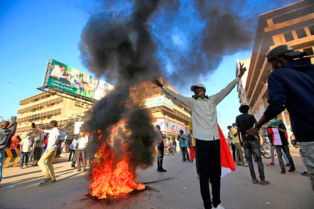 A Sudanese man flashes the V for victory sign in front of burning tyres during protests in the capital Khartoum to mark the second anniversary of the start of a revolt that toppled the previous government, on Saturday  (AFP photo)