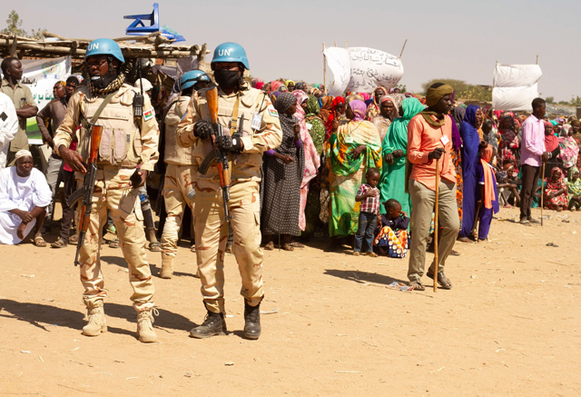 Members of the United Nations and African Union peacekeeping mission (UNAMID) look on as Sudanese internally displaced people stage a sit in to protest against the end of their mandate, in Kalma camp in Nyala, the capital of South Darfur, on Thursday  (AFP photo)