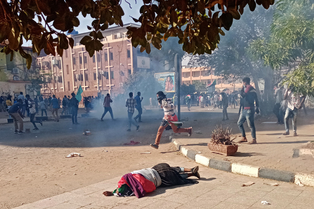 A wounded Sudanese protester falls on the pavement after security forces fired tear gas during a rally to mark three years since the start of mass demonstrations that led to the ouster of strongman Omar Al Bashir, in the capital Khartoum, on Sunday (AFP photo)