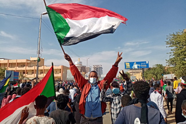 A Sudanese protester waves the national flag during a rally to mark three years since the start of mass demonstrations that led to the ouster of strongman Omar Al Bashir, in the capital Khartoum, on December 19 (AFP photo)