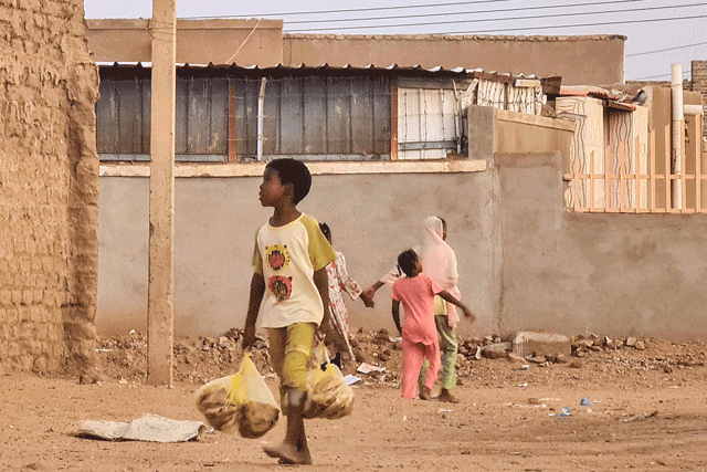 A child carries bags with bread as he walks in a street in Khartoum on Tuesday (AFP photo)