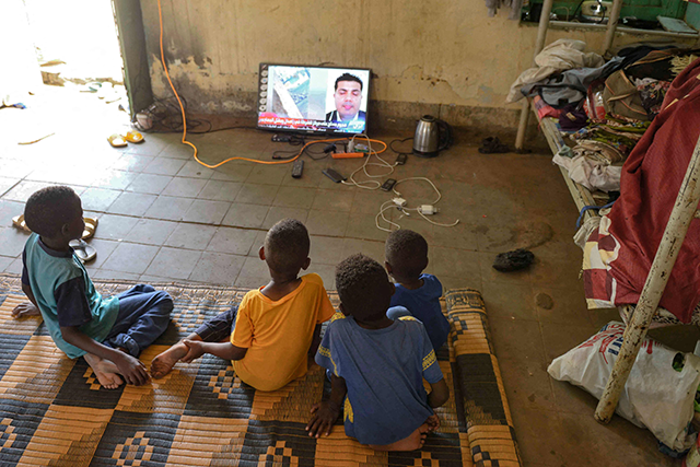 Displaced children who fled the ongoing violence by two rival Sudanese generals watch television in a room inside the university of Al Jazira, transformed into a makeshift shelter, in Al Hasaheisa, south of Khartoum, on Saturday (AFP photo)