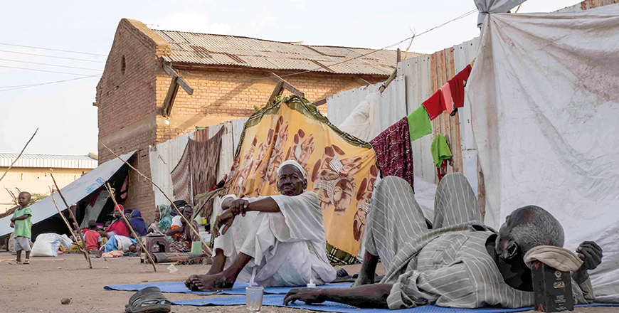 Men sit and lie outside tents and shelters pitched at the Hasahisa secondary school on Monday (AFP photo)