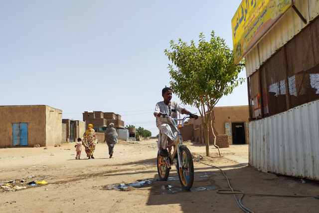A youth rides a bicycle on a street in Omdurman's Al Thawrat area on Sunday, as fighting continues in war-torn Sudan (AFP photo)