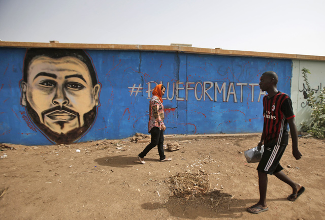 Sudanese activist Eythar Gubara (left) walks in front of a mural painting of Mohamed Mattar, on the wall of a youth club in Bahri in the capital Khartoum’s northern district, on Sunday  (AFP photo)
