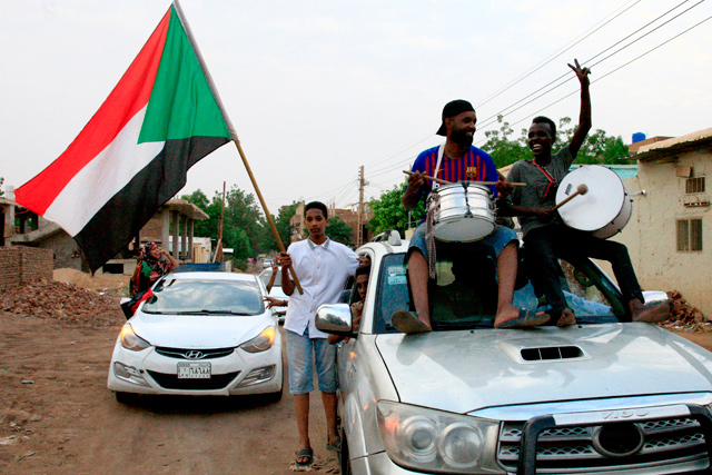 Sudanese demonstraters wave their national flag as they celebrate in Khartoum early on Saturday, after Sudan’s ruling generals and protest leaders reached a full agreement on the constitutional declaration (AFP photo)