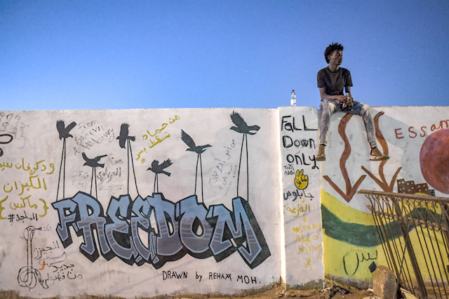 In this file photo taken on April 20, a Sudanese protestor sits on a wall covered in graffitti during a protest outside the army complex in the capital Khartoum (AFP photo)