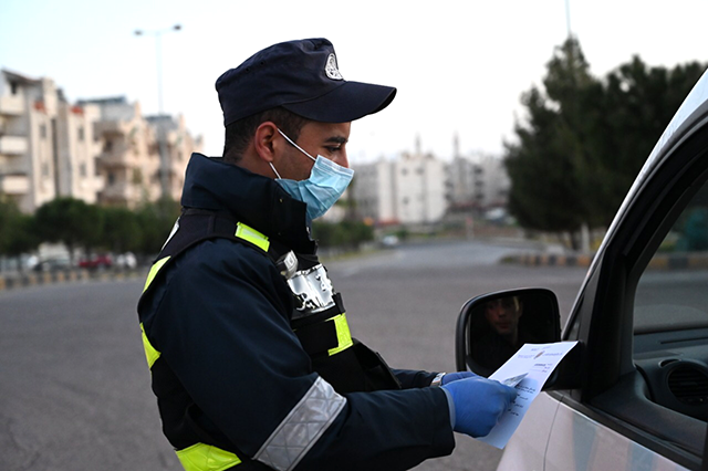 A police officer checks the papers of a motorist while manning a street in Amman during the nationwide curfew, imposed to curb the spread of the coronavirus, in this recent photo (Photo by Amjad Ghsoun)