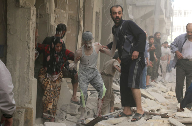 Syrians help a wounded youth following an air strike on the Fardous rebel-held neighbourhood of the northern Syrian city of Aleppo on Tuesday (AFP photo)