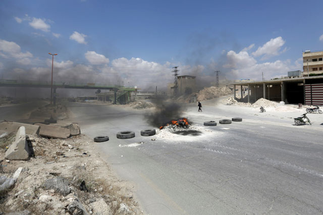 A gunman walks near burning tyres as protesters block Damascus-Aleppo highway during a protest against rising oil prices in the rebel-controlled area of Maaret Al Numan town in Idlib province, Syria, on Thursday (Reuters photo)