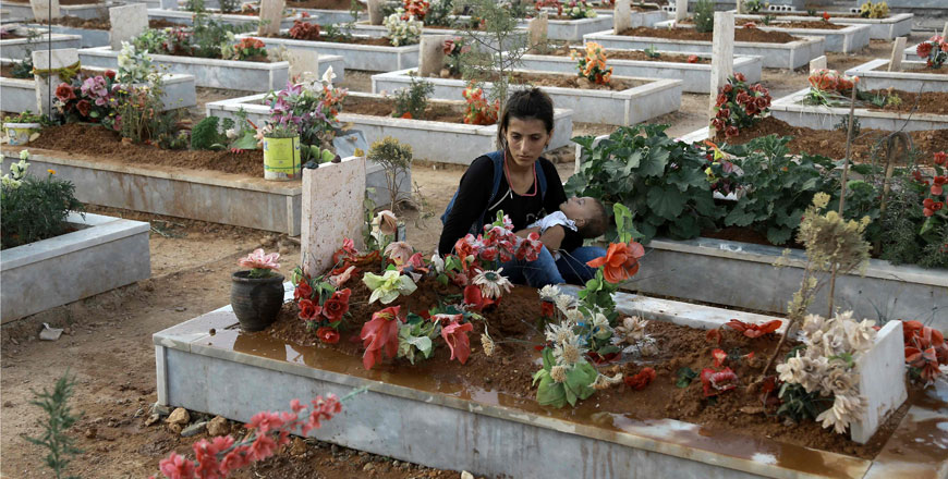 A Syrian Kurdish woman mourns next to the grave of a relative at a cemetery in the Syrian Kurdish town of Kobane  (Ain Al Arab) on Friday (AFP photo)
