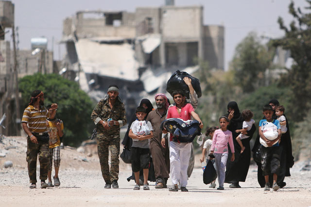 Syria Democratic Forces (SDF) fighters walk with people that fled their homes due to clashes between Daesh militants and SDF towards safer parts of Manbij, in Aleppo Governorate, Syria, on Sunday  (Reuters photo)