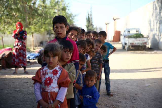 Syrian children, who fled with their families from the village of Hawsh Nasri in Douma, queue to receive aid from an NGO in the village of Shaffuniya in Ghouta, east of the capital Damascus, on Saturday (AFP photo)