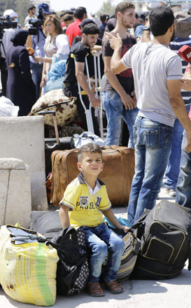 Syrian civilians from the town of Daraya are evacuated from the rebel-held town of Moadamiyet Al Sham on Thursday to be taken to a shelter in the government-controlled town of Harjala (AFP photo)