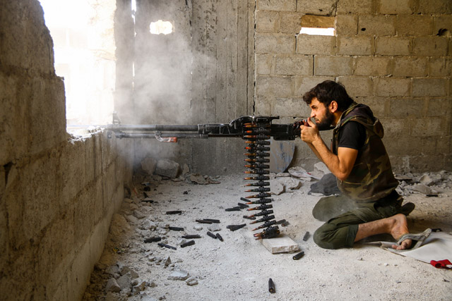 A member of opposition forces  fires from a building during a clash after government forces reportedly hit a rebel-held region,  Ain Tarma town, in the Eastern Ghouta region of Damascus, Syria, on Monday (Anadolu Agency photo)