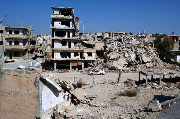 In this picture taken Friday, a car drives through a devastated part of the old city of Homs, Syria. Some 1,200 rebels and civilians, many of them wounded and starving from a year-long siege, withdrew from the last remaining strongholds in the ancient heart of Homs in May 2014, surrendering to President Bashar Assad a bloodstained city once dubbed the ‘capital of the revolution’ (AP photo)
