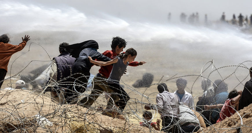 Syrian refugees flee as Turkish soldiers use water cannons to move them away from fences at the Turkish border, near the Syrian town of Tel Abyad in Sanliurfa province, on Friday (AFP photo)