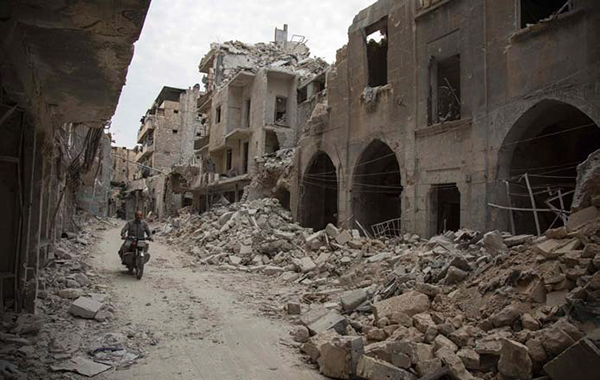 A Syrian man rides his motorbike past destroyed buildings on Monday, in Aleppo's Bab Al Hadid neighbourhood which was targeted recently by regime air strikes (AFP photo)