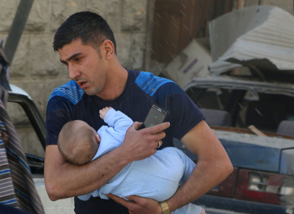 A man evacuates a baby from a site hit by air strikes in the rebel-held area of Aleppo’s Al Fardous district, Syria, on Friday (Reuters photo)