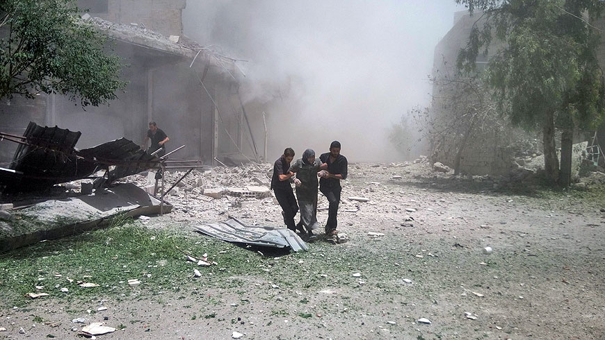 A cloud of dust is seen after a building collapsed as a Syrian woman is helped to leave the area following reported air strikes on Saturday in the town of Kfar Batna, on the outskirts of the capital Damascus (AFP photo)