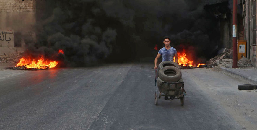 This July 31, 2016 photo, provided by the Syrian anti-government activist group Aleppo Media Centre, shows a Syrian young man burns tyres in an attempt to prevent air strikes above Aleppo, Syria (AP photo)