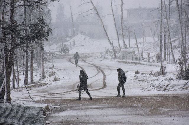 Syrian pro-government forces walk as snow falls in Aleppo on Wednesday (AFP photo)