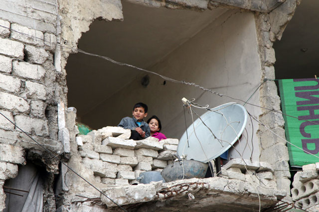 In this Thursday photo, children peer from a partially destroyed home in Aleppo (AP photo)