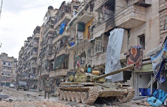 Syrian regime forces celebrate in front of heavily damaged and abandoned buildings in the former rebel-held Sukkari district in the northern city of Aleppo on Friday after Syrian government forces retook control of the whole embattled city (AFP photo)