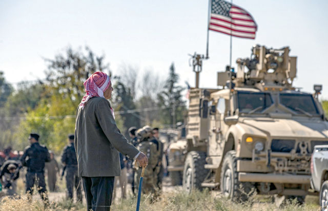 An elderly man watches as a US military vehicle, part of a joint convoy with the Kurdish People's Protection Units (unseen) patrols near the town of Al Muabbadah in the north-eastern Syrian Hasakeh province on the border with Turkey on Saturday (AFP photo)