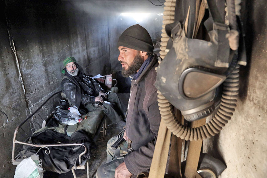 Abu Mahmoud, a 52-year-old rebel fighter, speaks with a fellow fighter next to gas masks inside a tunnel, used as a base, in the rebel-controlled area of Arbeen, on the outskirts of the Syrian capital Damascus, on Friday (AFP photo)