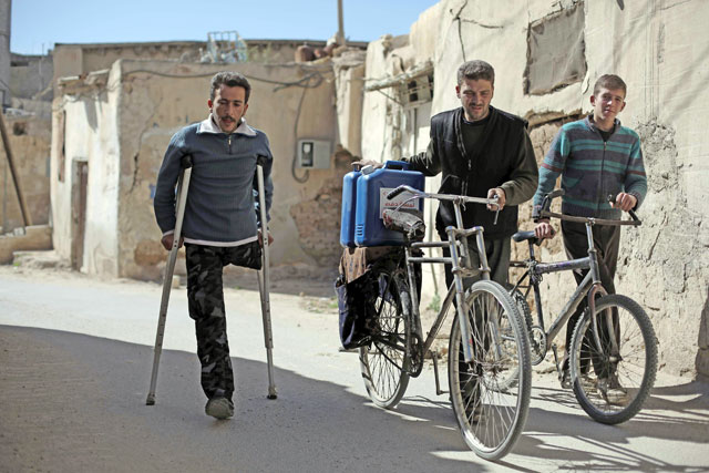 Syrians carry aid, in the form of diesel fuel, delivered by the Qatari Red Crescent in the rebel-held town of Beit Sawa, on the outskirts of the capital Damascus, on Monday (AFP photo)