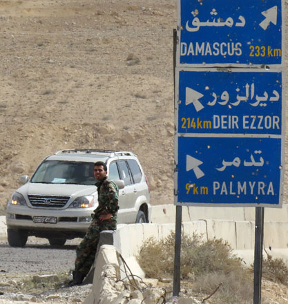A member of the Syrian government forces sits by a sign post on the outskirts of the ancient city of Palmyra, after they recaptured the UNESCO world heritage site from the Daesh terror group on Sunday (AFP photo)