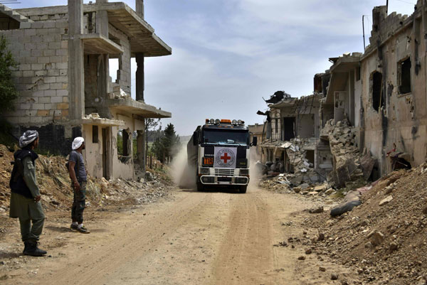 An aid truck of the International Committee of the Red Cross drives past destroyed buildings in the rebel-held village of Teir Maalah, on its way to Talbisseh, on the northern outskirts of Homs in central Syria, on Monday (AFP photo)