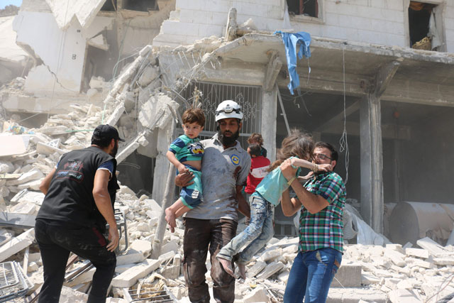 Syrian civilians and a rescue worker evacuate children in the Maadi district of eastern Aleppo after regime aircraft reportedly dropped explosive-packed barrel bombs on Saturday (AFP photo)