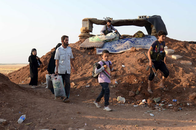Syrian families, fleeing Daesh militants and the ongoing fighting, carry their belongings on Monday as they arrive to take refuge in the Syrian village of Al Khalfatli, held by the Free Syrian Army, near the Syrian-Turkish border, north of Aleppo (AFP photo)