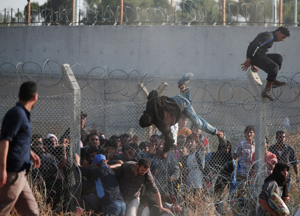 In this June 14, file photo, Syrian refugees cross into Turkey from Syria over and through a hole on the border fence in Akcakale, Sanliurfa province, southeastern Turkey (AP photo)