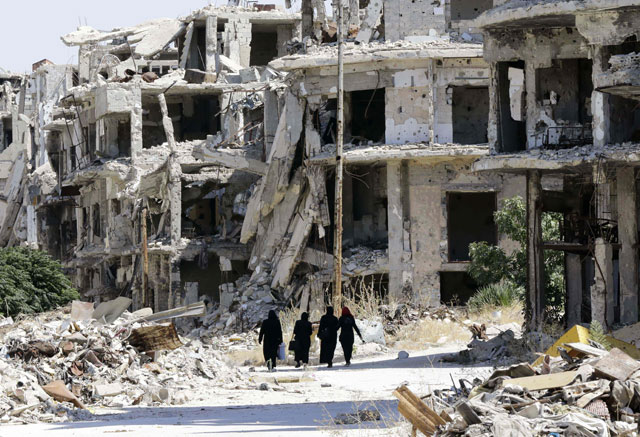 Syrian women walk in between destroyed buildings in the government-held Jouret Al Shiah neighbourhood of the central Syrian city of Homs on Monday (AFP photo)