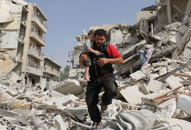 A Syrian man carries a baby after removing him from the rubble of a destroyed building following a reported air strike in the Qatarji neighbourhood of the northern city of Aleppo on  Wednesday (AFP photo)